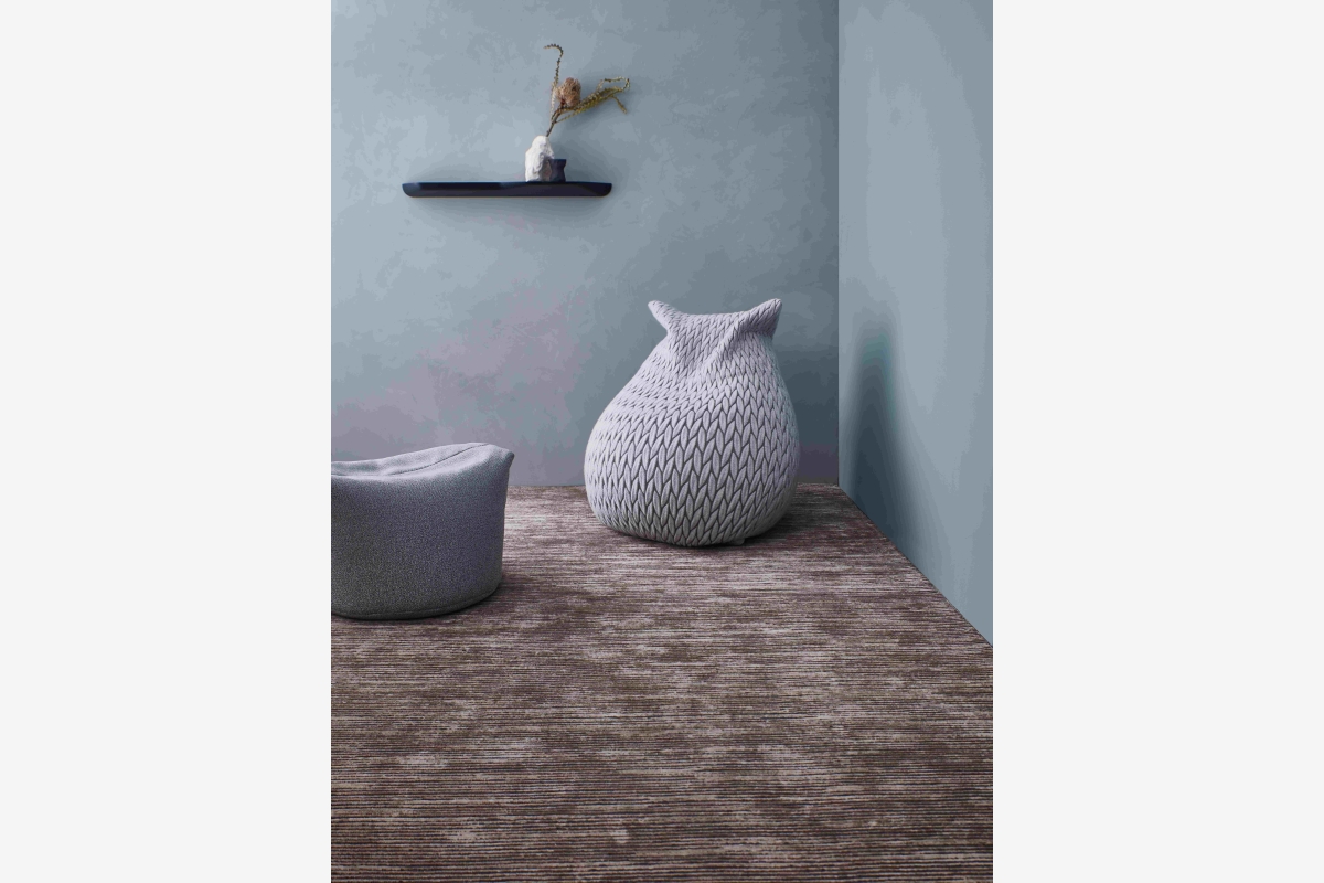Grijze decoratieve uilenfiguur met textuur staat op een houten plank.