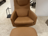 Cognackleurige leren fauteuil met hoofdsteun en bijpassende voetenbank op een ta