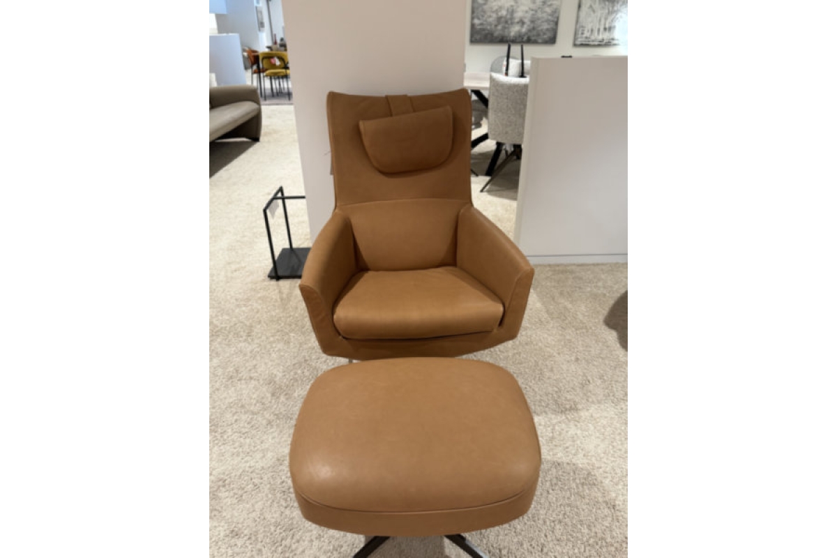 Cognackleurige leren fauteuil met hoofdsteun en bijpassende voetenbank op een ta