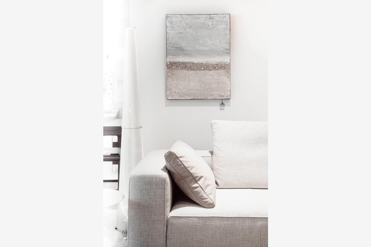 Moderne muurdecoratie met abstracte print boven een witte gestoffeerde bank.