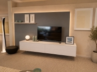 Woonkamer met wit zwevend tv-meubel, wandpaneel en een staande lamp.