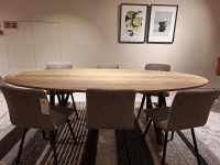 Ovale houten eettafel met zes gestoffeerde stoelen op een gestreepte vloerbedekk