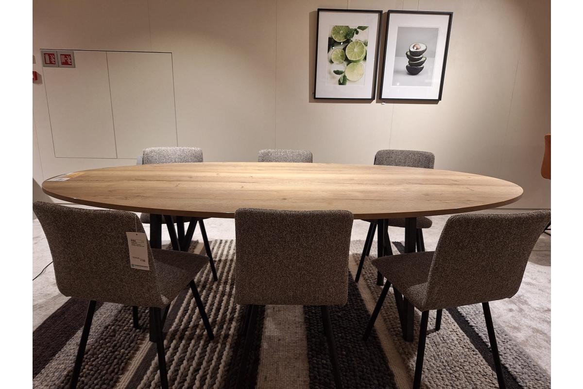 Ovale houten eettafel met zes gestoffeerde stoelen op een gestreepte vloerbedekk