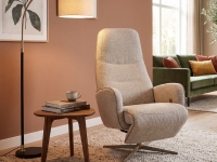 Beige fauteuil in een woonkamer met een salontafel, boeken, kopje en een staande