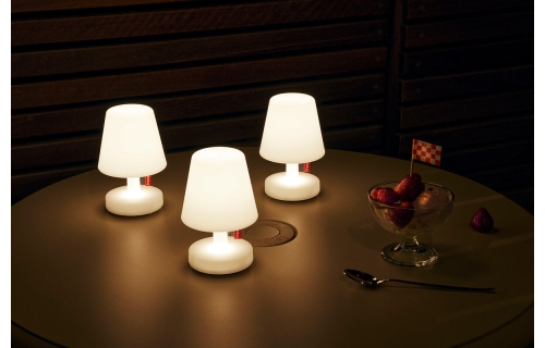 Drie oplaadbare tafellampen met witte kap en voetstuk op een ronde tafel met des