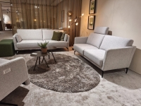 Een lichte zithoek met twee grijze banken en een bijpassende fauteuil, met een g