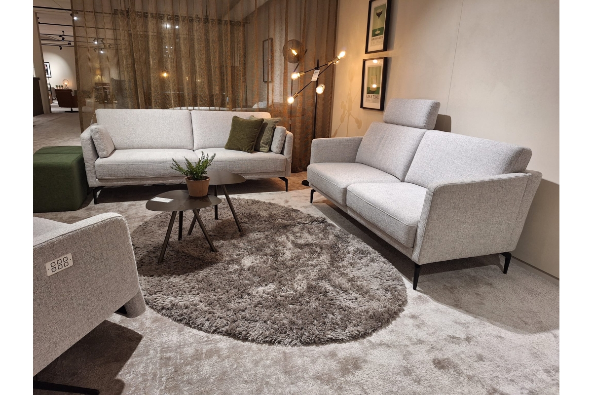 Een lichte zithoek met twee grijze banken en een bijpassende fauteuil, met een g