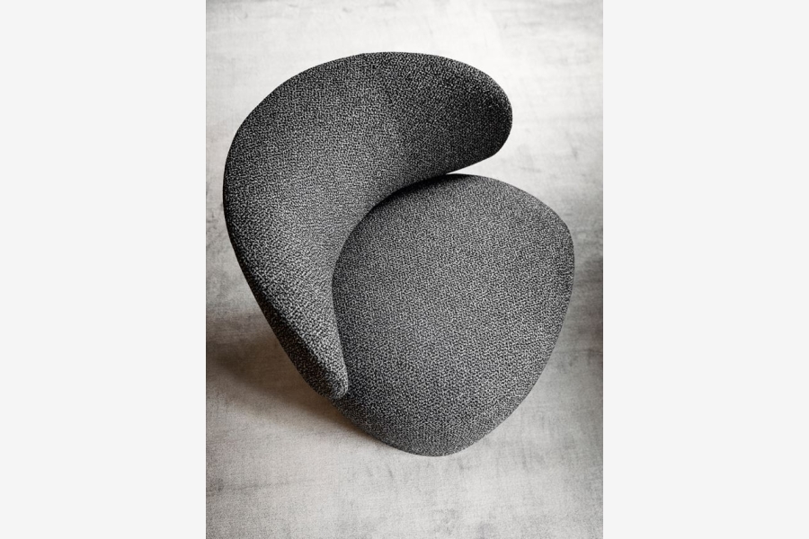 Gedetailleerde weergave van de grijze, gestoffeerde armleuning van een fauteuil.