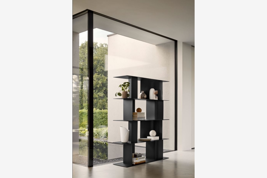 Zwarte wandplank met verschillende decoratieve objecten, tegen een witte muur naast een raam.