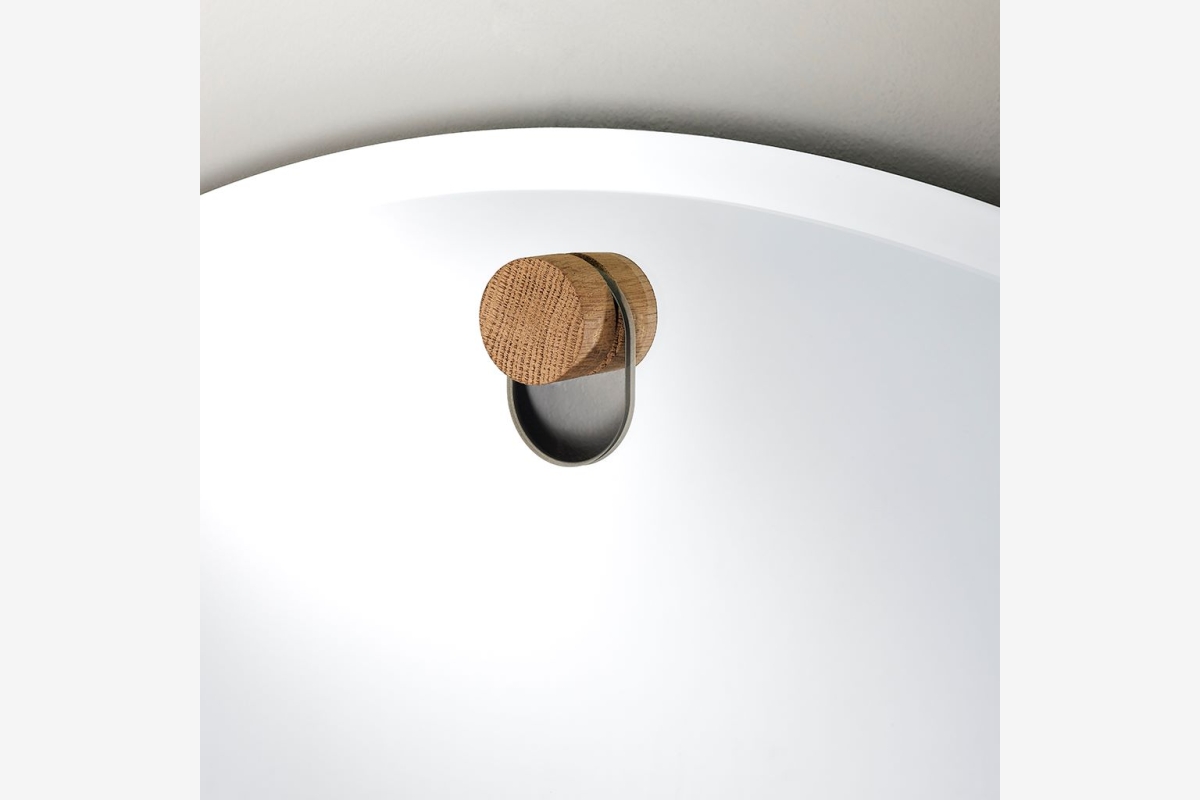 Detail van een rond handvat van licht hout op een witte lade of deur.