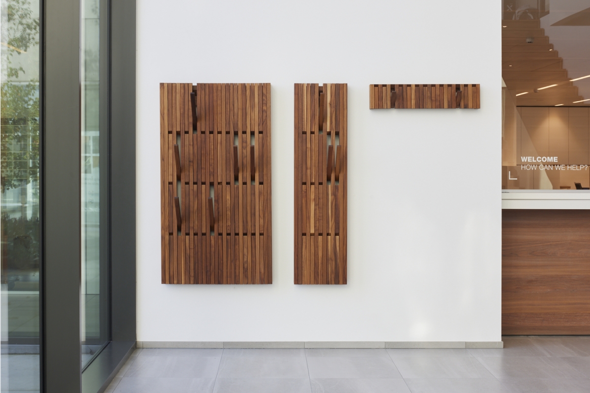 Drie decoratieve houten panelen aan een witte muur naast een raam.
