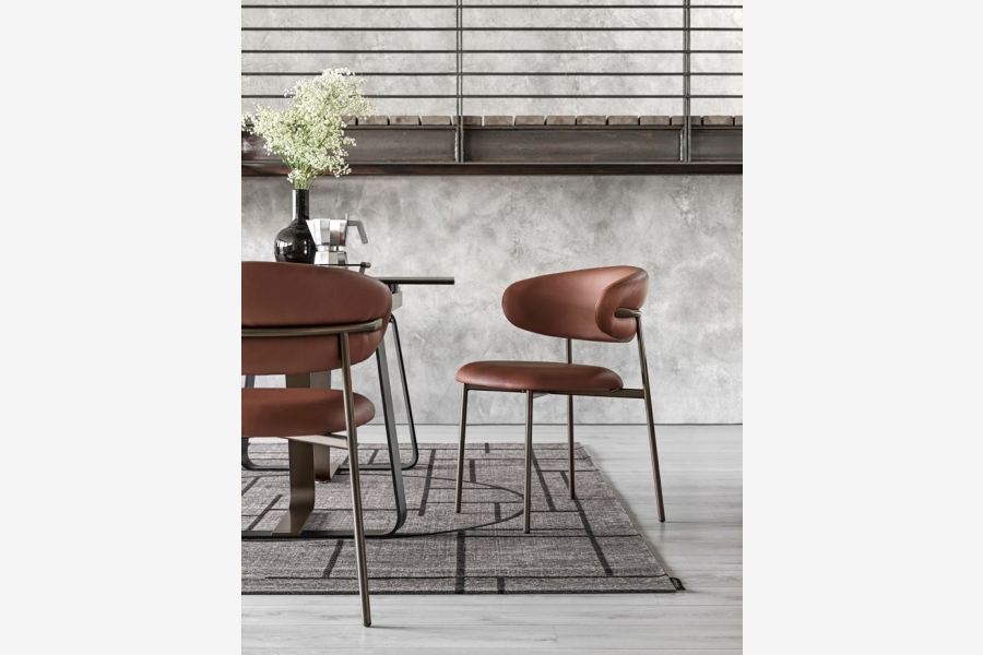 Okerkleurige stoel met een zachte rugleuning en zitting staat naast een eettafel.
