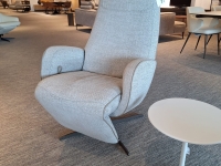 Lichtgrijze relaxfauteuil met hoge rugleuning en een wit bijzettafeltje op een k