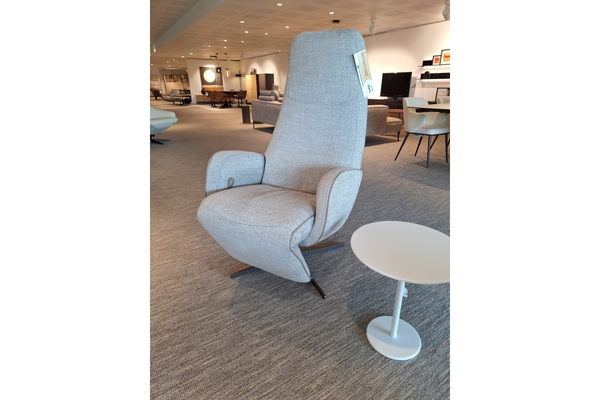 Lichtgrijze relaxfauteuil met hoge rugleuning en een wit bijzettafeltje op een k