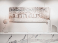 Lange, marmeren dressoirkast met een abstract schilderij en een ronde tafellamp.