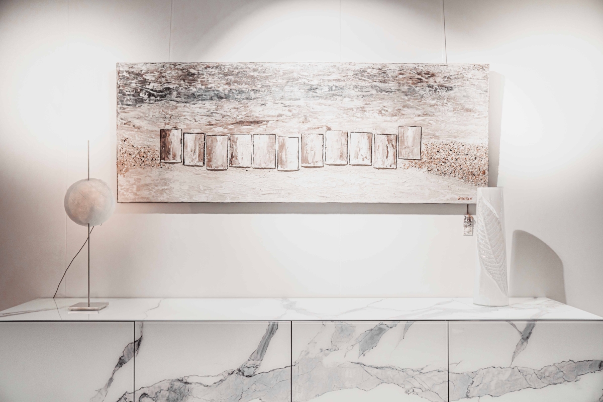 Lange, marmeren dressoirkast met een abstract schilderij en een ronde tafellamp.