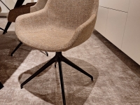 Beige stoel met stoffen bekleding en een zwart onderstel met vier poten.