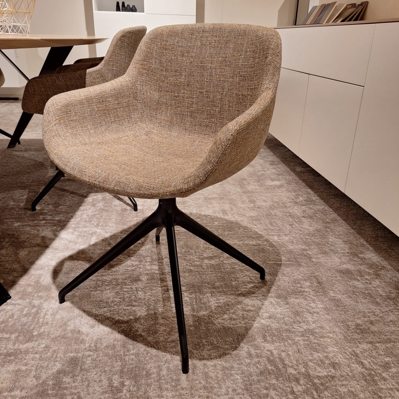 Beige stoel met stoffen bekleding en een zwart onderstel met vier poten.