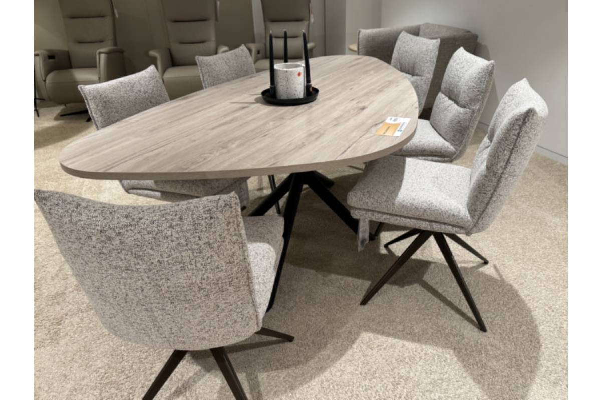 Ovale eettafel met houtnerf en zes stoffen eetkamerstoelen met draaivoet in een